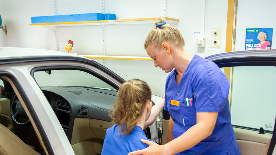 Linnea och Camilla demonstrerar hur träning för att komma i och ur en bil kan se ut.